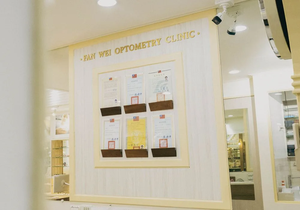 牆面的 FAN WEI OPTOMETRY CLINIC 證照展示區,木框內陳列多張驗光人員證書