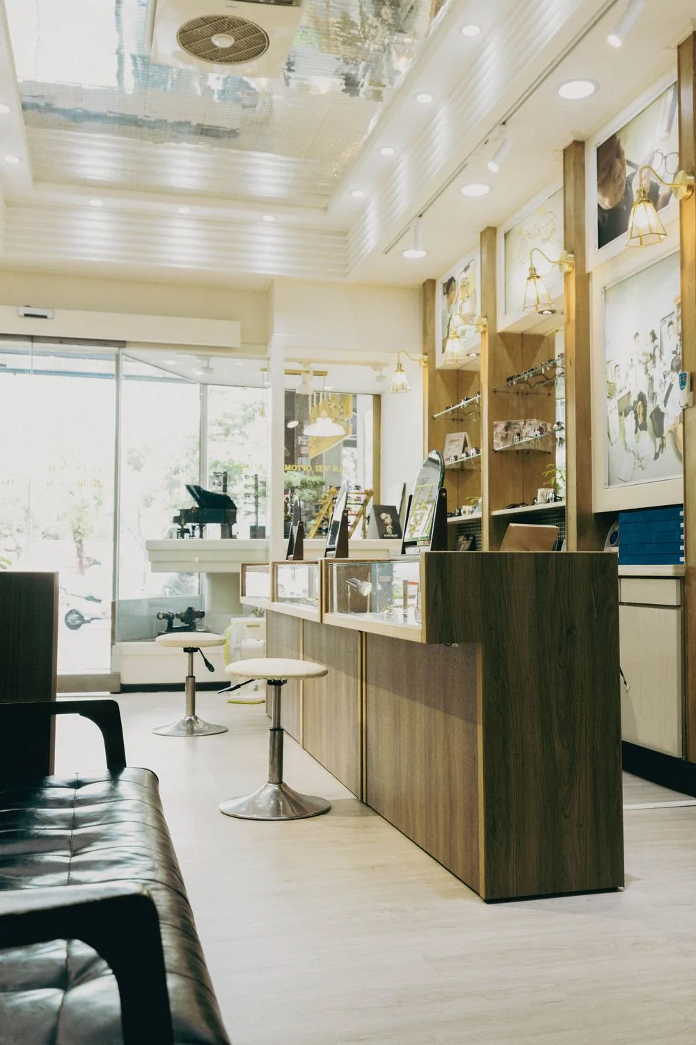 店內陳列一景:玻璃展示櫃、白色圓凳與牆面家族照片燈箱
