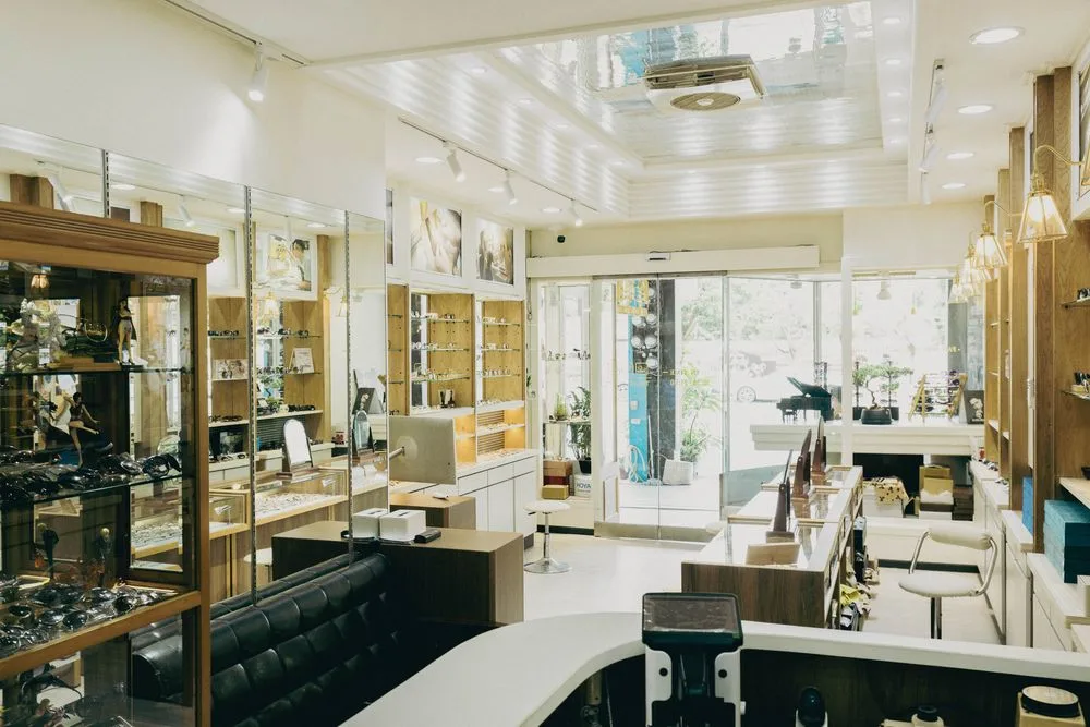 店內全景:木質展示櫃、玻璃陳列櫃、黑色皮革長椅與挑高天花板