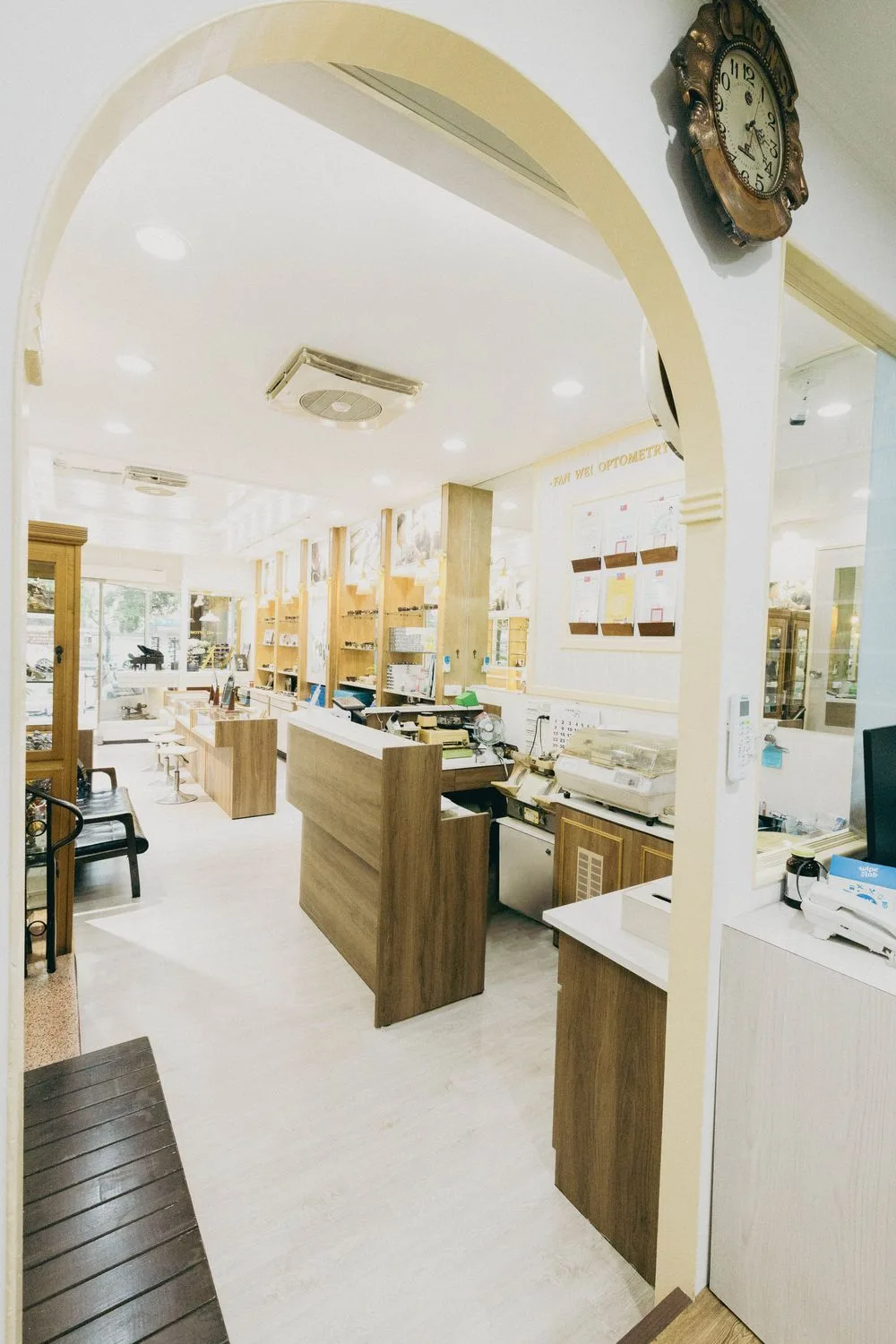 從拱門望向店內:木質櫃檯、老件工作機具與牆面證照區