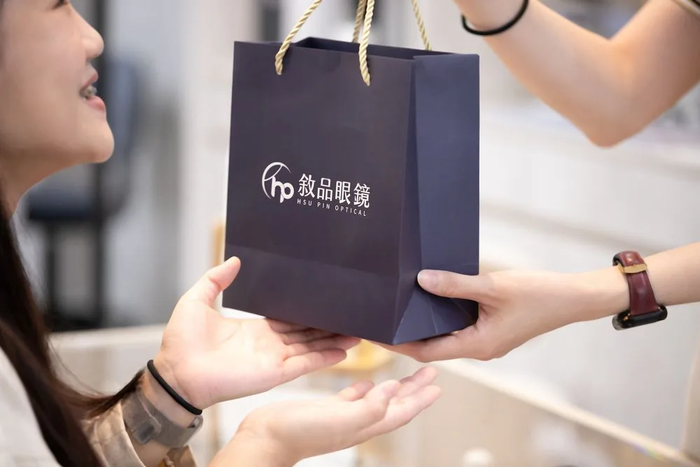門市人員將敘品眼鏡提袋交到顧客手中