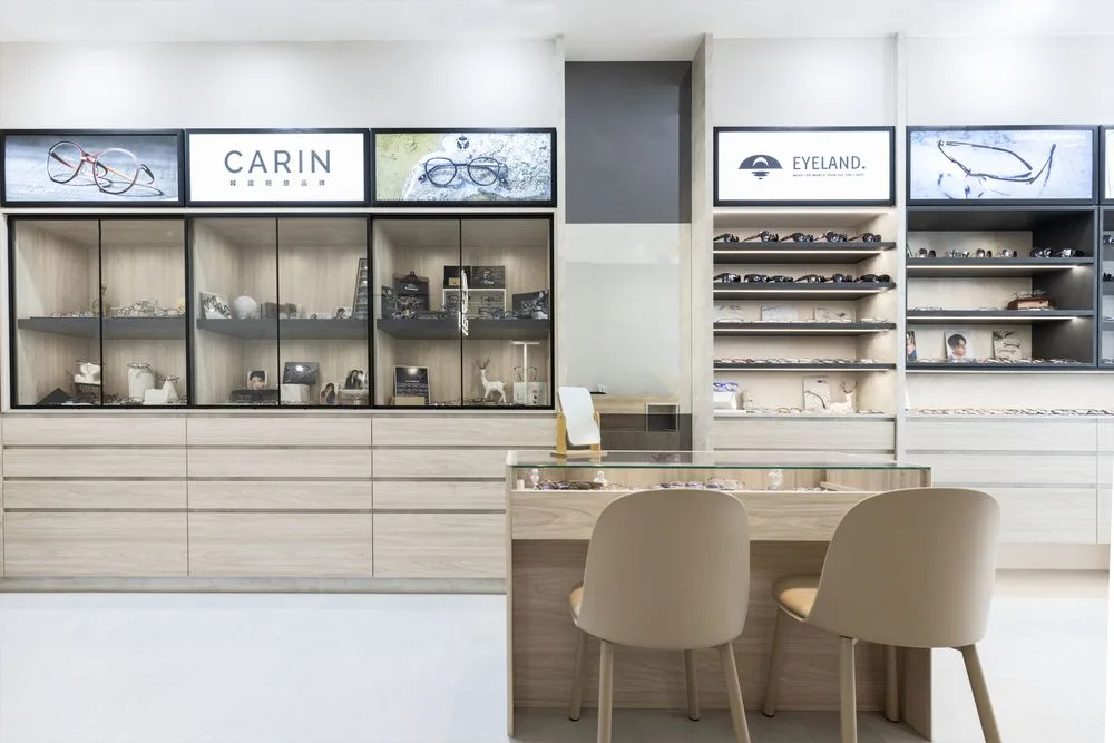 CARIN 與 EYELAND 品牌區全景:玻璃展示櫃、開放層架與中央玻璃試戴桌