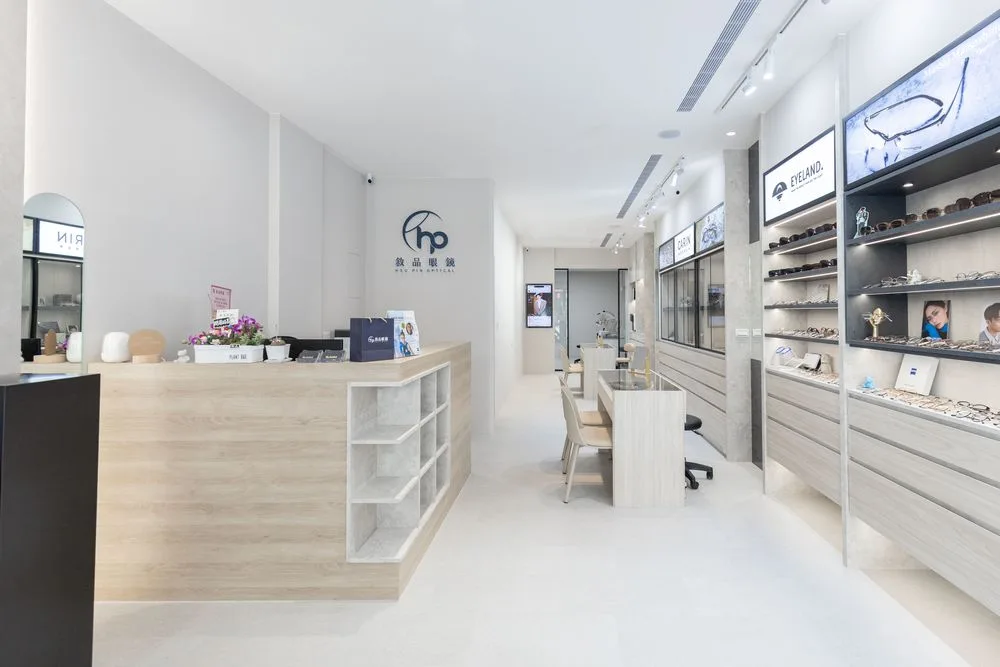 敘品眼鏡店內全景:淺色木質櫃檯、hp 標誌牆與右側 EYELAND、CARIN 品牌陳列牆