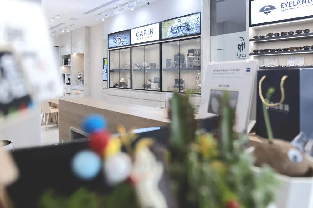 玻璃展示櫃與 CARIN 品牌燈箱牆,前景為櫃檯花藝擺飾