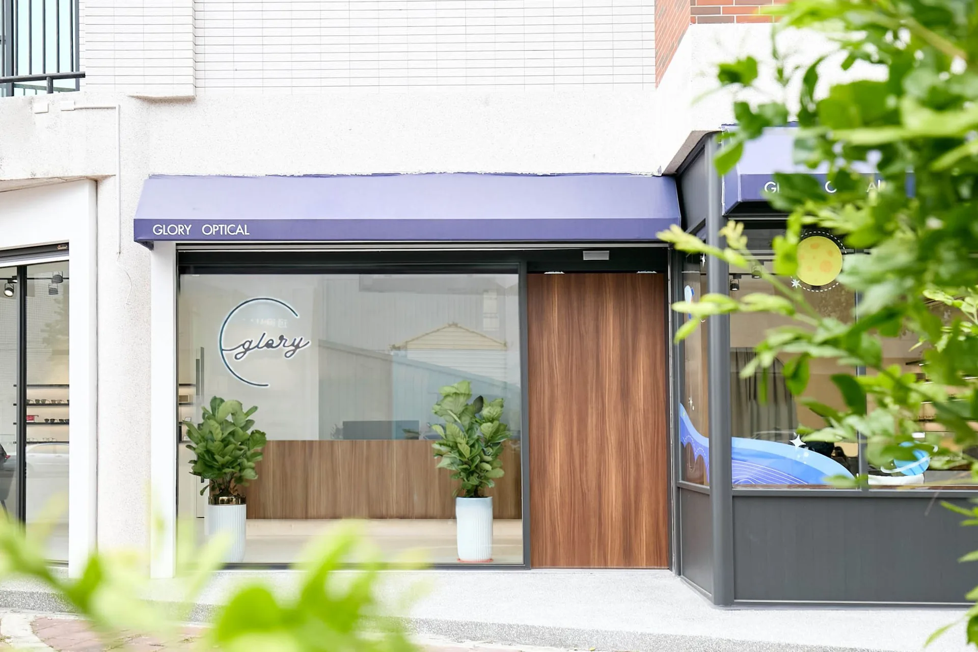 虎尾宏恩眼鏡榮耀視光中心店面外觀，藍紫色 GLORY OPTICAL 雨遮與整面落地玻璃窗