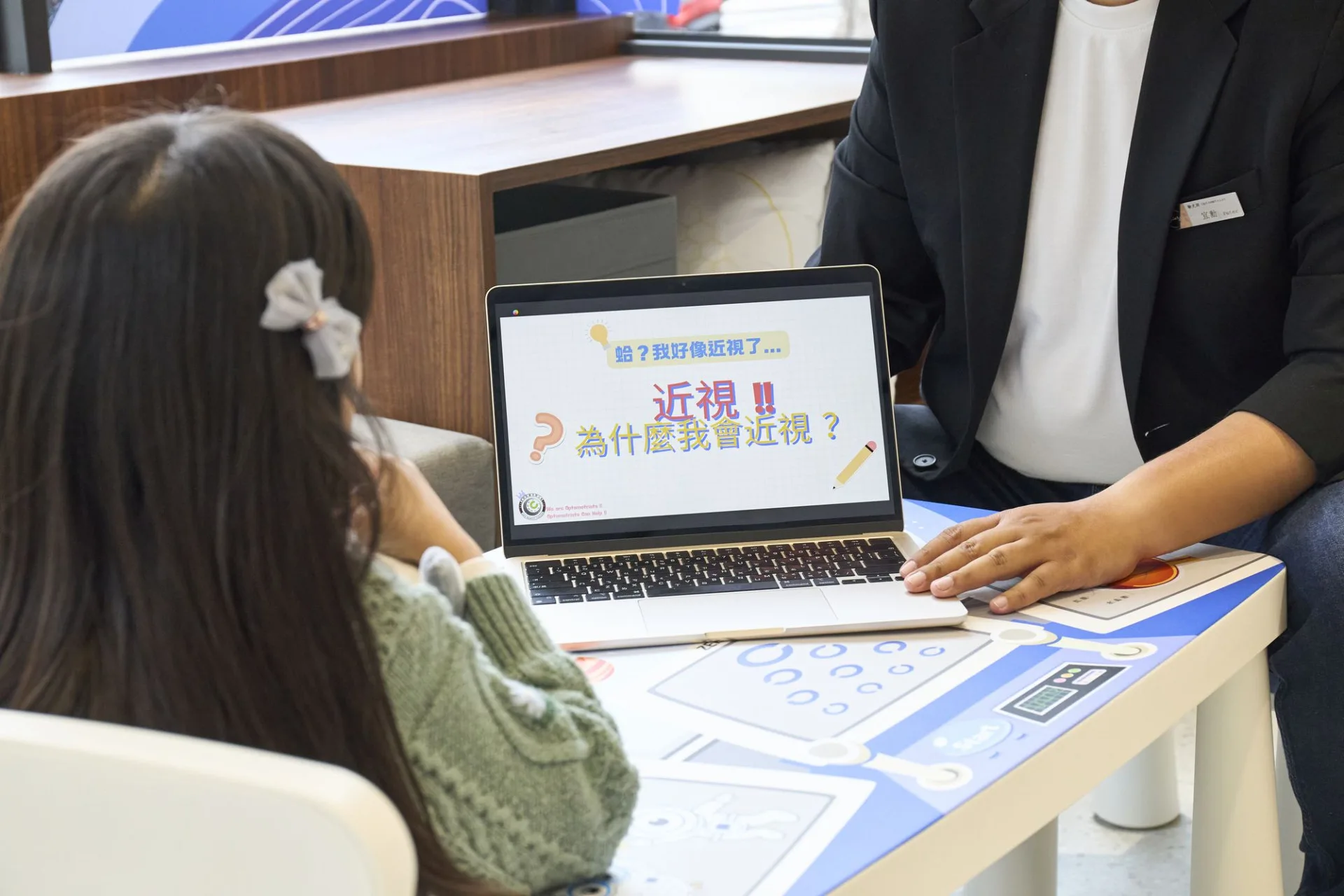 門市人員以筆電向孩童說明近視形成原因的衛教簡報