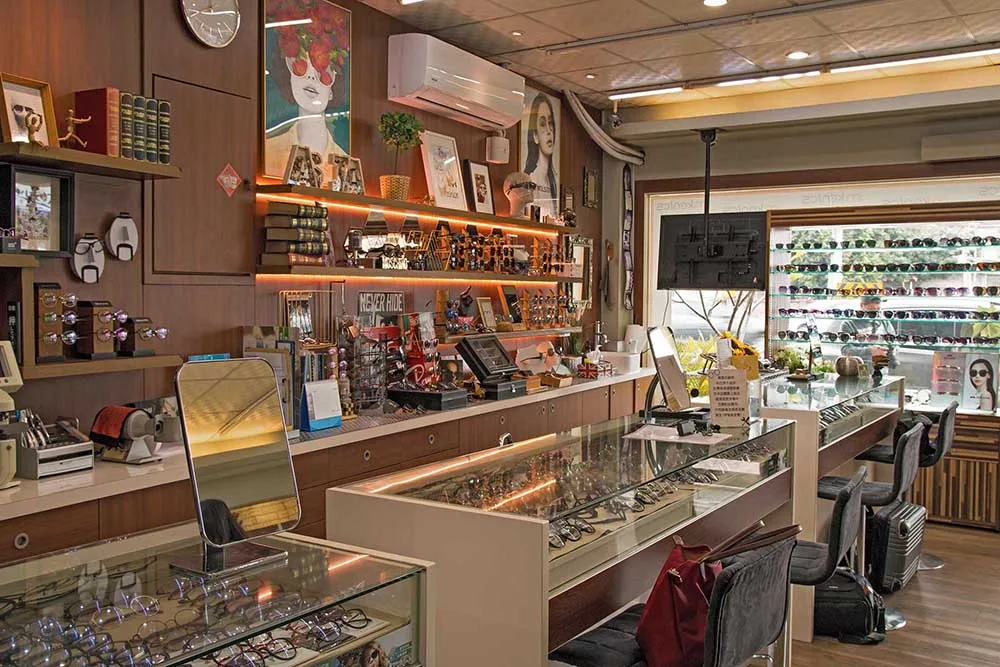 店內木質調全景:層架暖光、玻璃陳列櫃與窗邊墨鏡牆