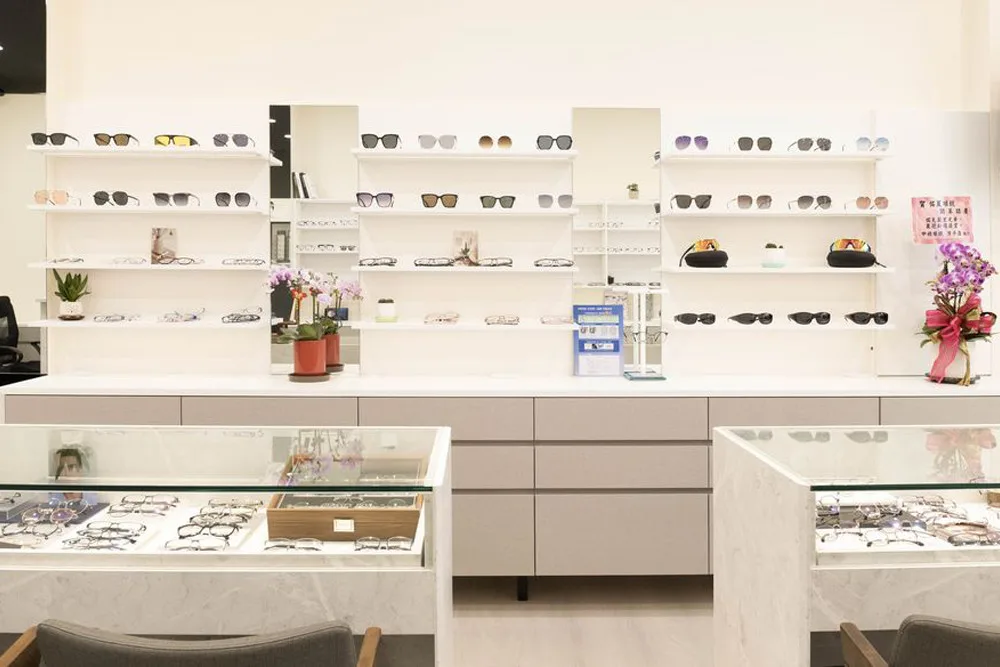 墨鏡與鏡框陳列牆全景:玻璃展示櫃、蘭花盆栽與層架照明