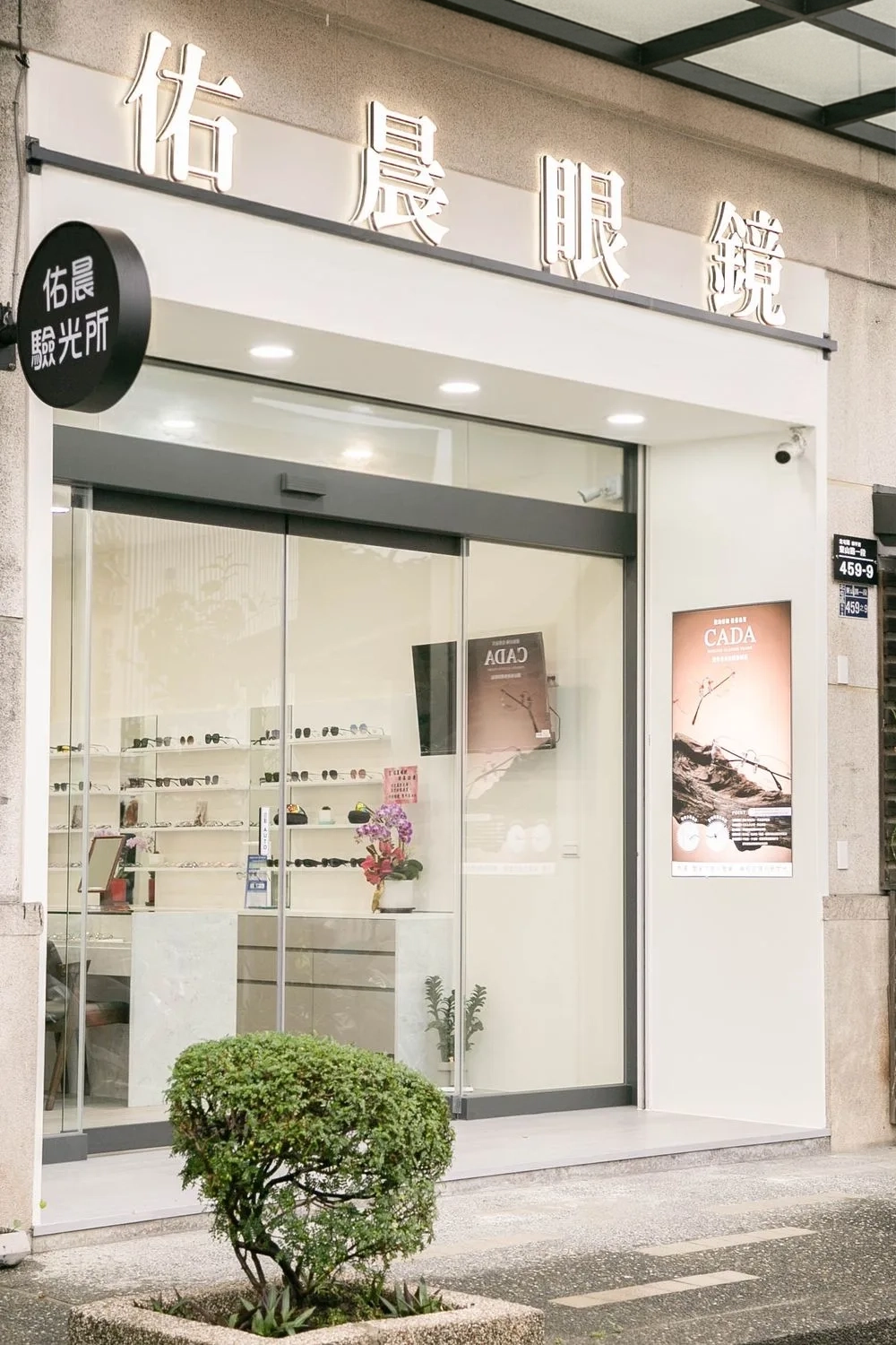 佑晨眼鏡白色店面外觀:立體字招牌、佑晨驗光所圓招牌與整面玻璃櫥窗
