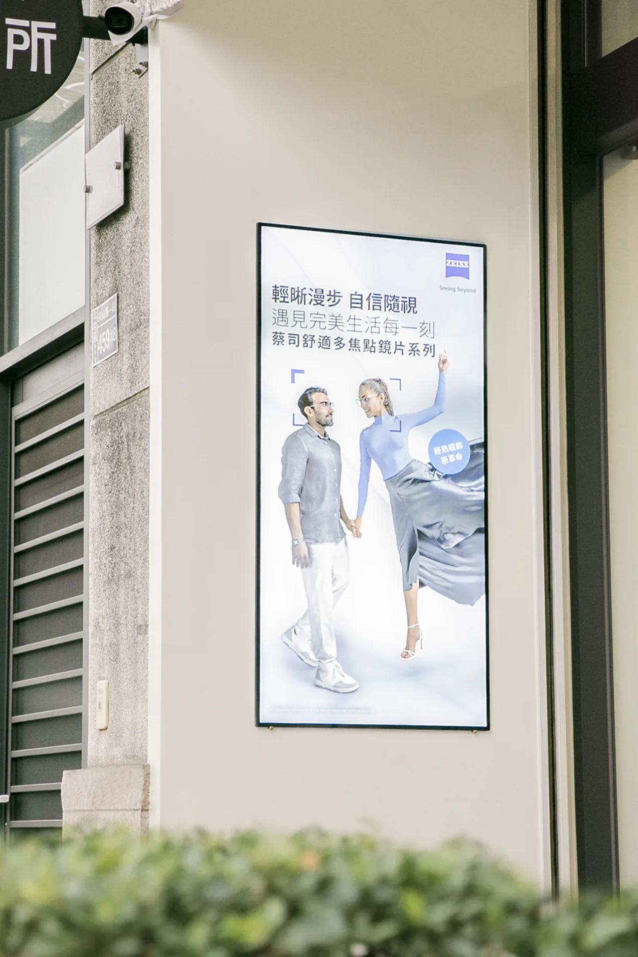 店外牆面的蔡司舒適多焦點鏡片系列燈箱廣告,上方可見佑晨驗光所圓形招牌一角