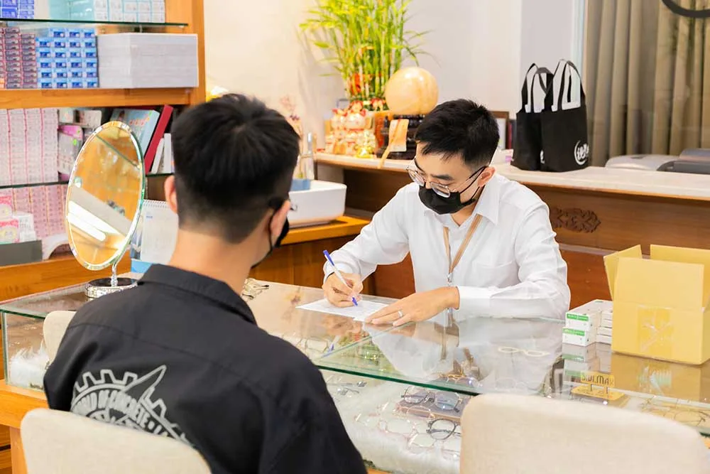 店員在玻璃櫃檯前為顧客填寫配鏡資料單