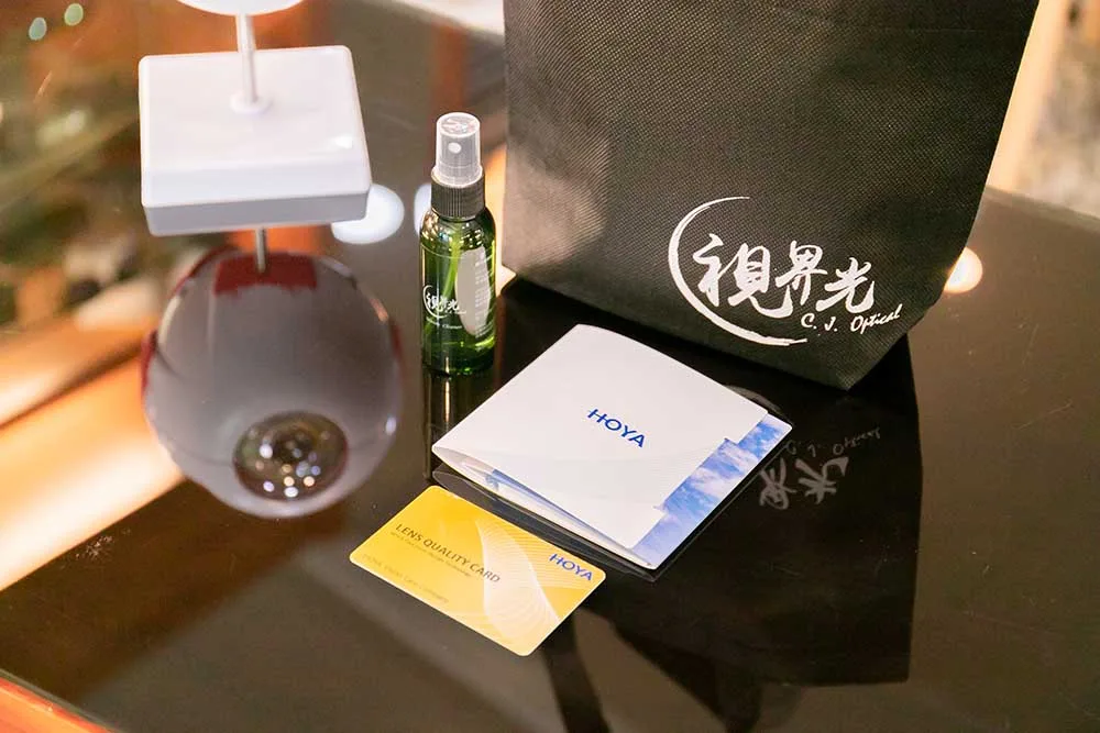 視界光提袋、鏡片清潔噴瓶與 HOYA 鏡片品質保證卡的交件組合