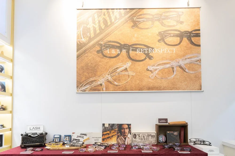 lash RETROSPECT 系列海報牆，紅絨展示桌上陳列復古鏡框與打字機
