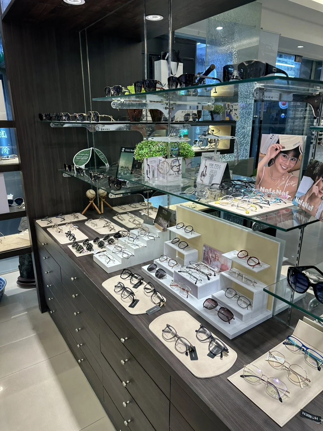 校園眼鏡店內鏡框展示櫃,多個品牌鏡框陳列於玻璃層板