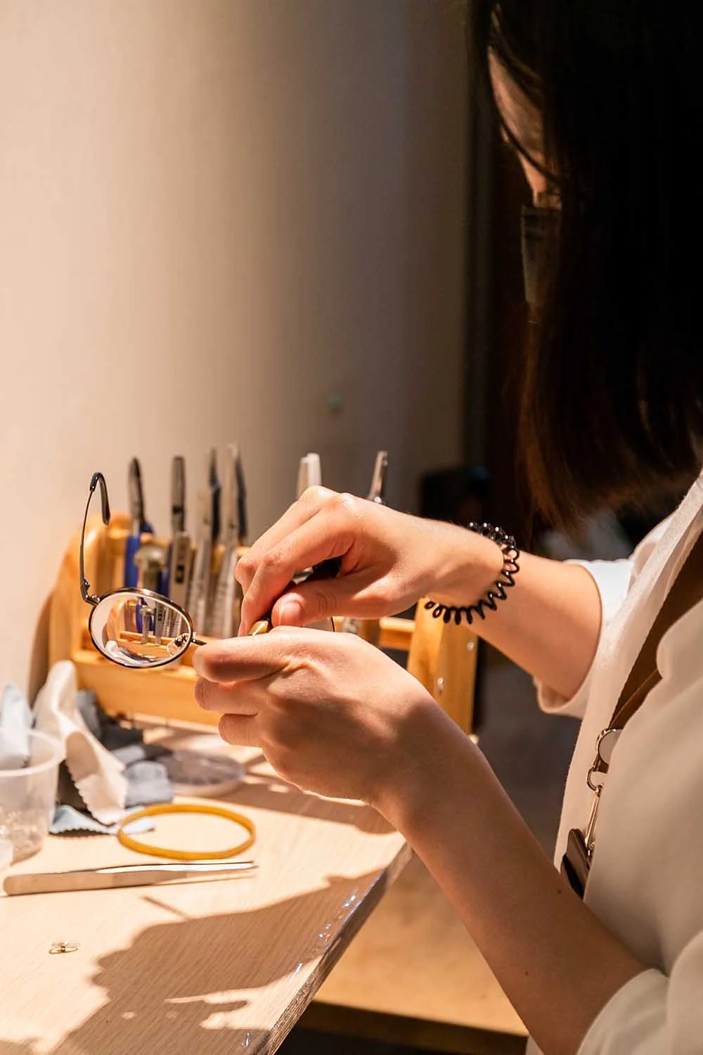 視界光眼鏡以工具手工調整金屬鏡框，後方為木製工具架