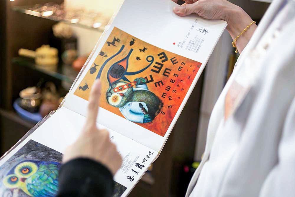 翻開的畫冊,印著店裡的貓頭鷹畫作